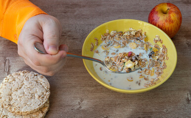 Fresh granola, muesli for breakfast. man eats cereal with milk from a plate. concept of proper nutrition and a healthy lifestyle. Useful mixtures remarkably remove harmful substances, slags.