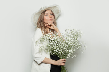 Attractive woman wearing summer hat holding flowers on white background
