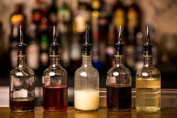 Bottles filled with syrups for mixing cocktails on bar counter. Alcohol drinks ingredients....
