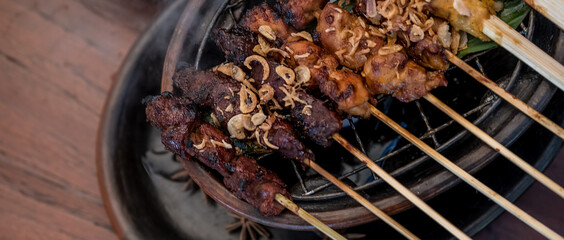 Satay or sate, skewered grilled meat, served with peanut sauce and spicy sauces. Malaysia or Indonesia food. Asian cuisine.