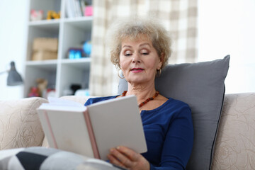 Grandmother sits at home and reads with enthusiasm