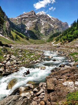 Manali, India - June 14th 2019: Crossing river by ropes in a scenic valley with huge mountains and blue sky  