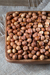 Hazelnuts in brown bowl on rustic wooden background.