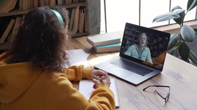 Virtual teaching concept. Smiling female young hispanic school math teacher, college tutor look at laptop webcam talking in classroom give remote class online lesson by zoom conference computer call.