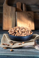 Almonds in round bowl on rustic wooden background 