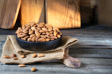 Almonds in round bowl on rustic wooden background 