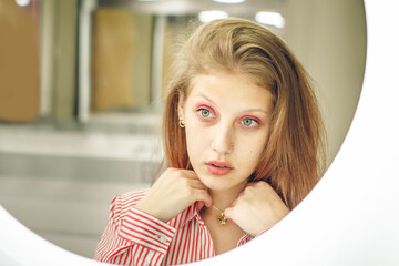 Girl looks in mirror. Attractive young blonde with red lips. Female self love, esteem and...