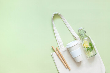 Cotton bag, thermos, glass bottle with lemon water and Melissa bamboo tubes. Let's go shopping. Ecological, natural materials.