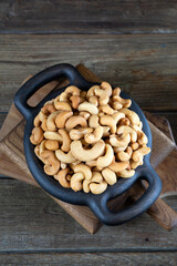 Cashew nuts in round bowl on wooden background 