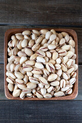 Pistachios in wooden bowl on rustic background 