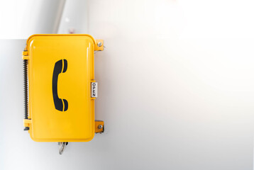 The yellow emergency phone on wall in public area of subway underground transport train station.