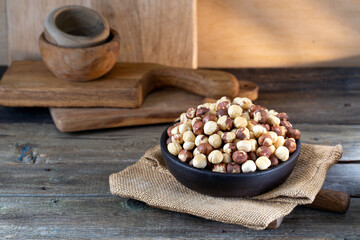 Hazelnuts in brown bowl on rustic wooden background.