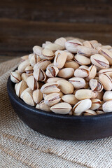 Pistachios in wooden bowl on rustic background 