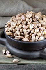 Pistachios in wooden bowl on rustic background 