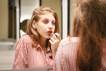 Girl looks in mirror. Attractive young blonde with red lips. Female self love, esteem and...