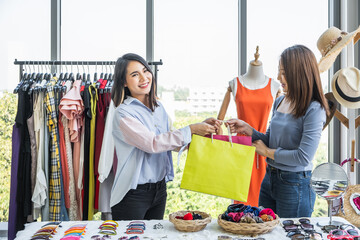 A sale woman handing shopping bags to customer inside a clothing fashion shop.