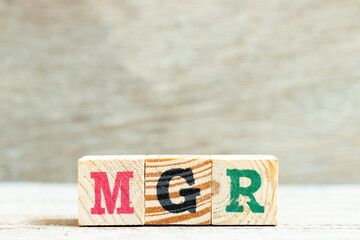 Alphabet letter in word mgr (abbreviation of manager) on wood background