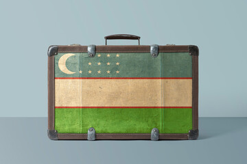 Uzbekistan flag on old vintage leather suitcase with national concept. Retro brown luggage with copy space text.