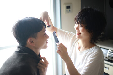 男性の髪を切る女性