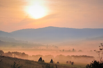 Morning fog over the field, beautiful mountains landscape.