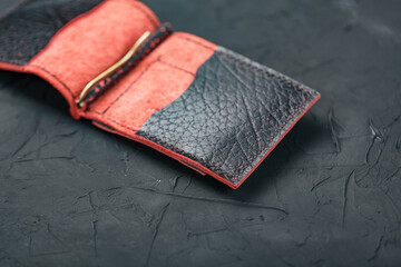 Red and black leather wallet on a black background.