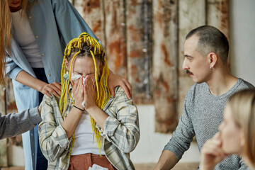 caucasian woman cry after heartbreaking story about alcoholism, members of anonymous alcoholics club surrounded her with care and attention