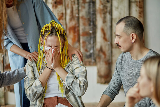 caucasian woman cry after heartbreaking story about alcoholism, members of anonymous alcoholics club surrounded her with care and attention