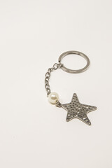 Useful items for the home. A small metal keyring with a starfish-shaped pendant and a small white pearl.