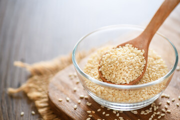 White sesame seeds in a wooden spoon on wood table.