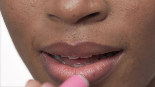 Close-up shot of woman applying pink lip balm and sending air kiss. Lips makeup, cosmetic product usage
