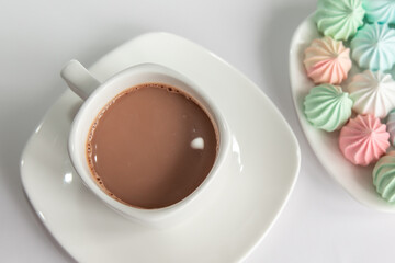 Multicolored meringues and a cup of coffee on a white background. isolated