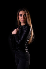 A young girl in a black leather jacket isolated on a black background