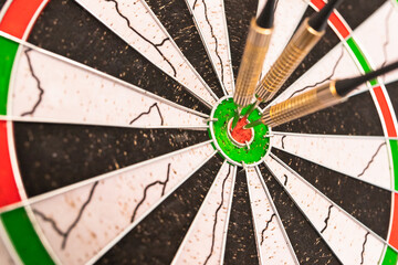Darts arrows in the target center. Dart in bulls eye of dartboard with shallow depth of field.