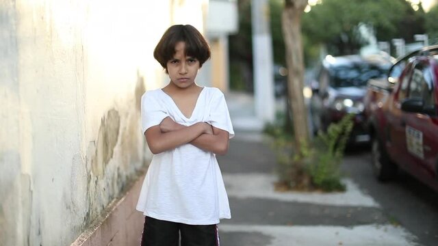 Upset child boy with arms crossed. Kid uncrossing arms looking to camera