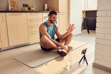 Cheerful gym instructor communicating with clients online from home