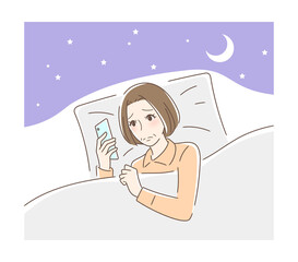 布団の中でスマホを見る不安そうな女性