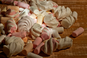 Lots of sweets on a wooden table. Pink marshmallows and bize close up. Candy on a shabby old board.