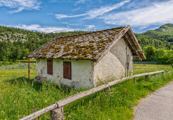 Fototapeta na wymiar Small wooden house in a green mountain valley of Trentino Alto Adige, northern Italy, Europe.