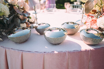 Presidium, table of the newlyweds. Floral arrangements of pink flowers. Silver candlesticks and candles. On the table is a pink velvet tablecloth. On the green lawn