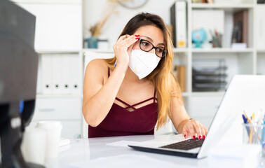 Young colombian woman in mask working with laptop