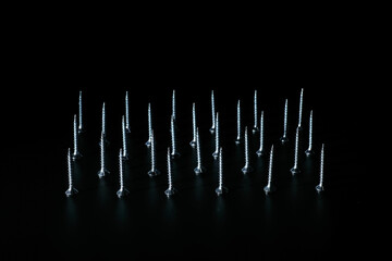 Zinc plated wood threaded screws standing in formation on black background
