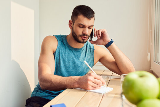 Handsome gentleman talking on cellphone and making notes