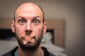Portrait of a man with a sealed mouth. The surprised guy can't speak. The concept of male...
