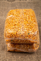 Yellow split peas in a cellophane bag on a background of coarse-textured burlap. Traditional grains for making soups and porridges. Close up.