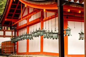 Red wooden buddhist temple with row of green hanging lanterns in Nara, Japan.