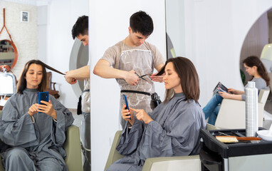 Woman using phone in hairsalon