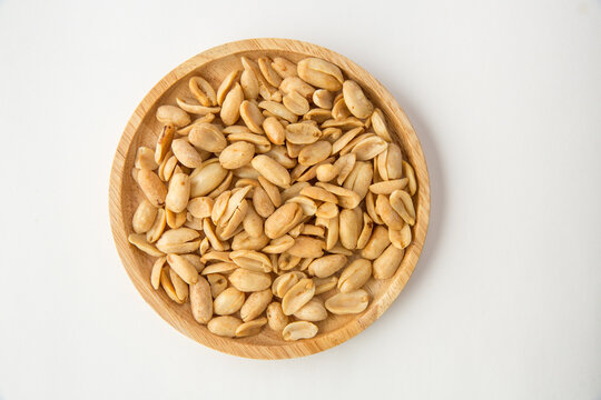 A pile of peanuts in a separate wooden dish on a white background top view