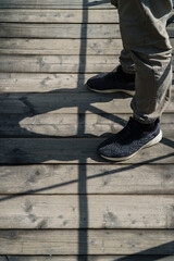 Male feet on an old wooden bridge cast a shadow
