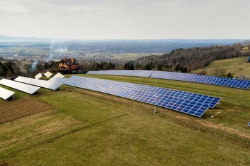 Aerial view of large field of solar photo voltaic panels system producing renewable clean energy on green grass background.