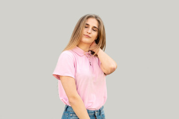 The young girl thought about something with her eyes closed. Dressed in a pink T-shirt. Isolated on gray background.